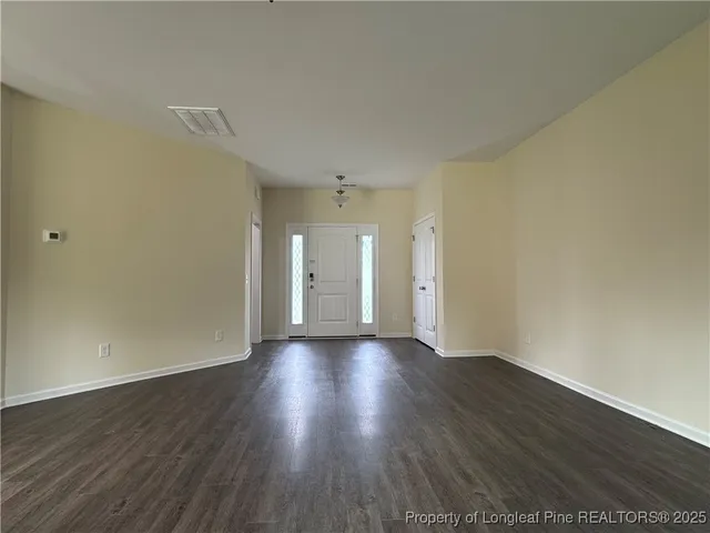 an empty room with wooden floor fireplace and windows