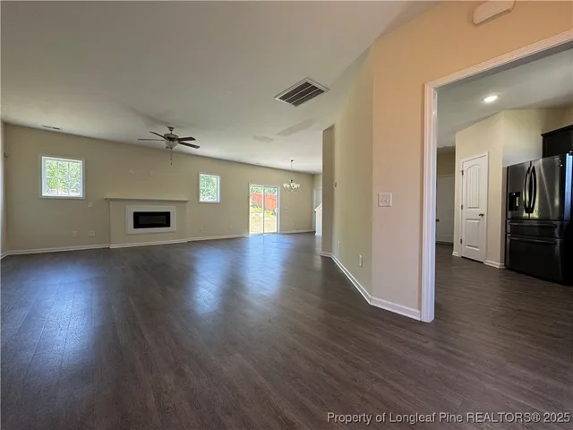 a view of an empty room with wooden floor a ceiling fan and a window