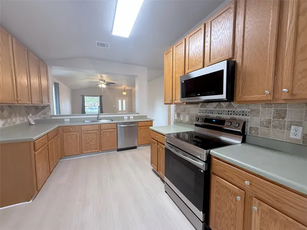 a kitchen with stainless steel appliances granite countertop a stove top oven a sink dishwasher a refrigerator and a microwave oven with wooden floor