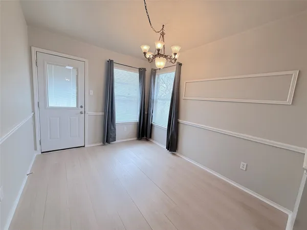 an empty room with chandelier fan and refrigerator