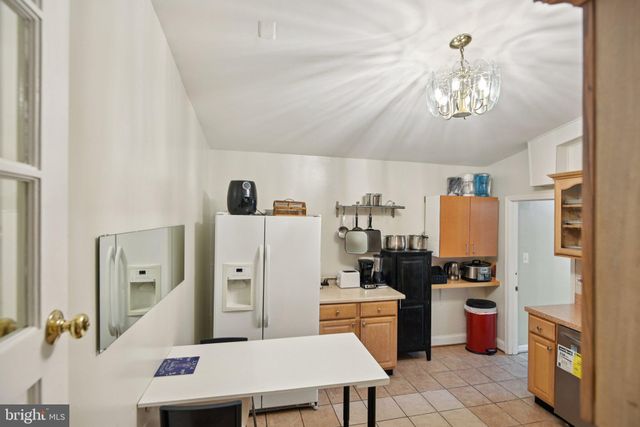 a kitchen with a refrigerator a stove a sink dishwasher and a dining table with wooden floor