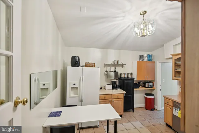 a kitchen with a refrigerator a stove a sink dishwasher and a dining table with wooden floor