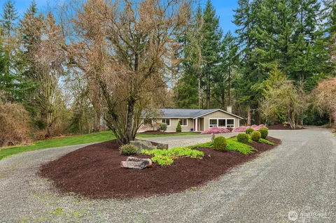 a view of a house with a yard and large trees