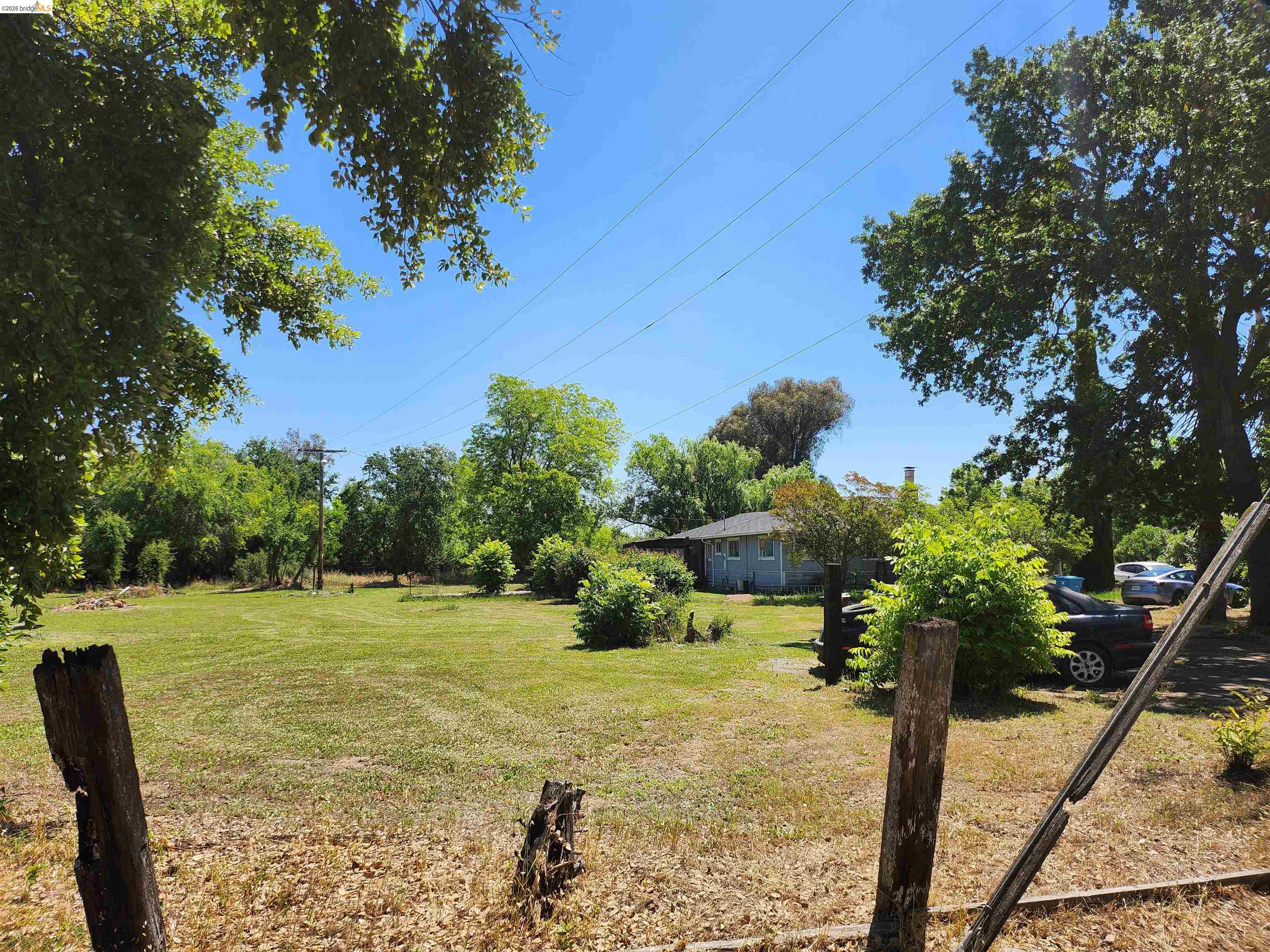 7750 Locke Road Vacaville, CA 95688 - Photo 16 of 23 Expansive grassy area with mature trees and a distant single-story structure