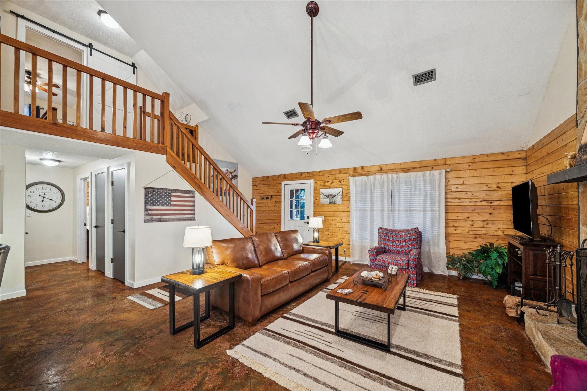 21538 Mueschke Road Tomball, TX 77377 - Photo 38 of 50 The living area of the cabin features a vaulted ceiling, exposed beams, and a stone fireplace that creates a warm and relaxing atmosphere. A loft space adds versatility for sleeping or storage, while natural textures and thoughtful design make this space feel like a true getaway. Perfect for guests or extended stays, this cabin combines comfort and character in every detail.