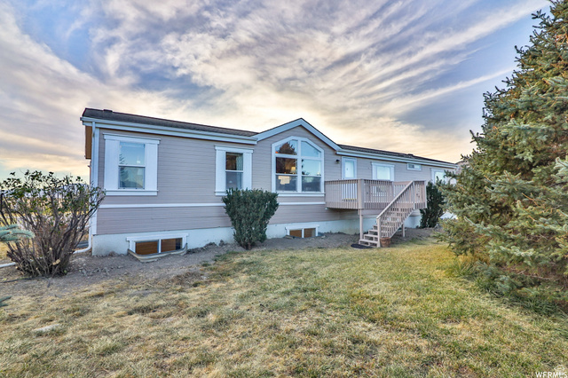 395 Walk Street Stockton, UT 84071 - Photo 1 of 1 Single-story residence featuring light gray siding, white window trim, and a prominent front deck with stairs
