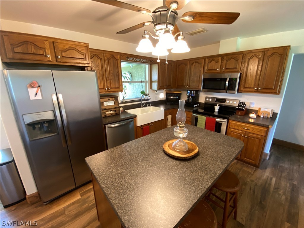 3501 Packinghouse Road Alva, FL 33920 - Photo 8 of 18 a kitchen with stainless steel appliances granite countertop a refrigerator a stove and a dining table with wooden floor