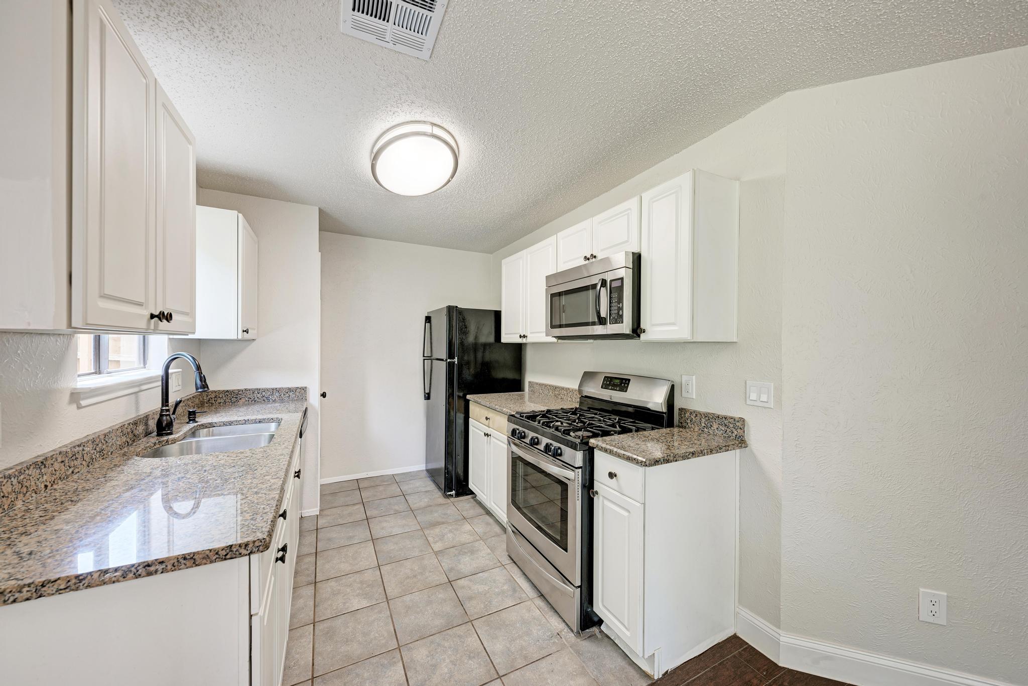 12108 Carnforth Drive Austin, TX 78753 - Photo 15 of 33 a kitchen with granite countertop a sink a stove top oven and cabinetry