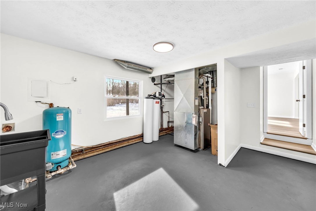 2928 Pressler Road Uniontown, OH 44685 - Photo 23 of 34 Exercise area featuring concrete floors, heating unit, a textured ceiling, and gas water heater