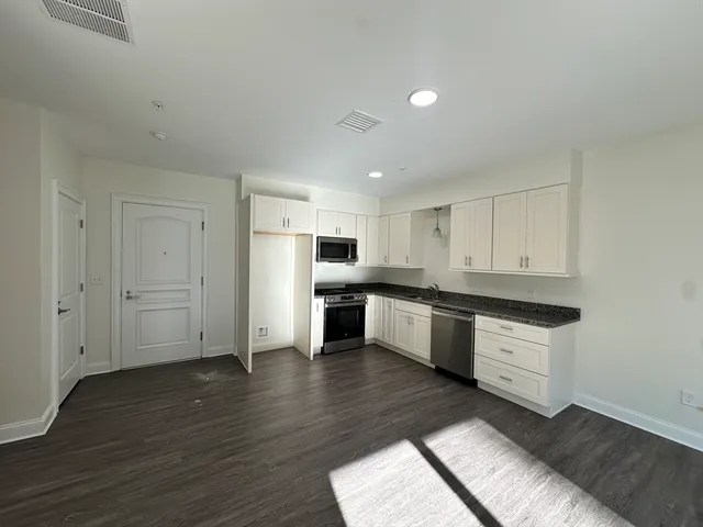 a large kitchen with cabinets wooden floor and stainless steel appliances