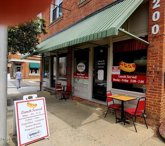an outdoor cafe with a table and chairs under an umbrella