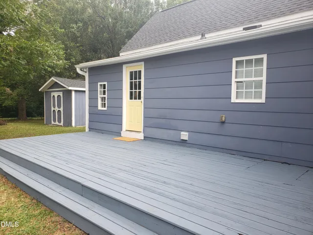 a view of a house with a wooden deck and a yard