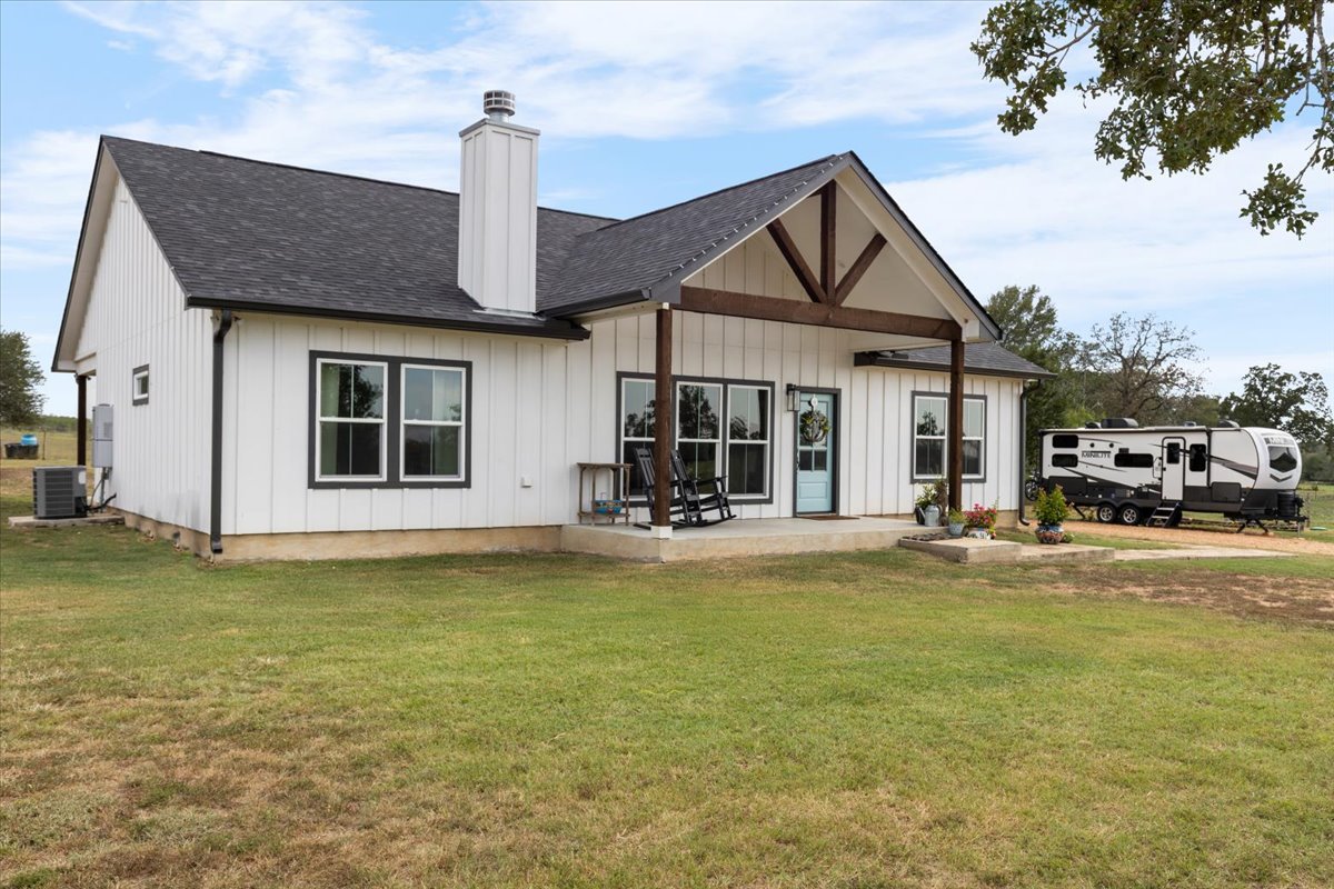 3389 Sparta Field Road Waelder, TX 78959 - Photo 24 of 40 Rear view of house with a chimney, roof with shingles, a lawn, a patio, and board and batten siding