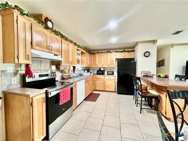 a kitchen with stainless steel appliances granite countertop a refrigerator and a stove top oven
