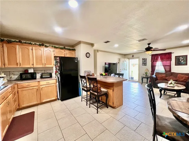 a kitchen with stainless steel appliances kitchen island granite countertop a refrigerator a stove a sink dishwasher and a dining table with the kitchen view