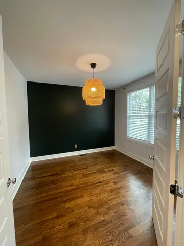 a view of an empty room with window and wooden floor