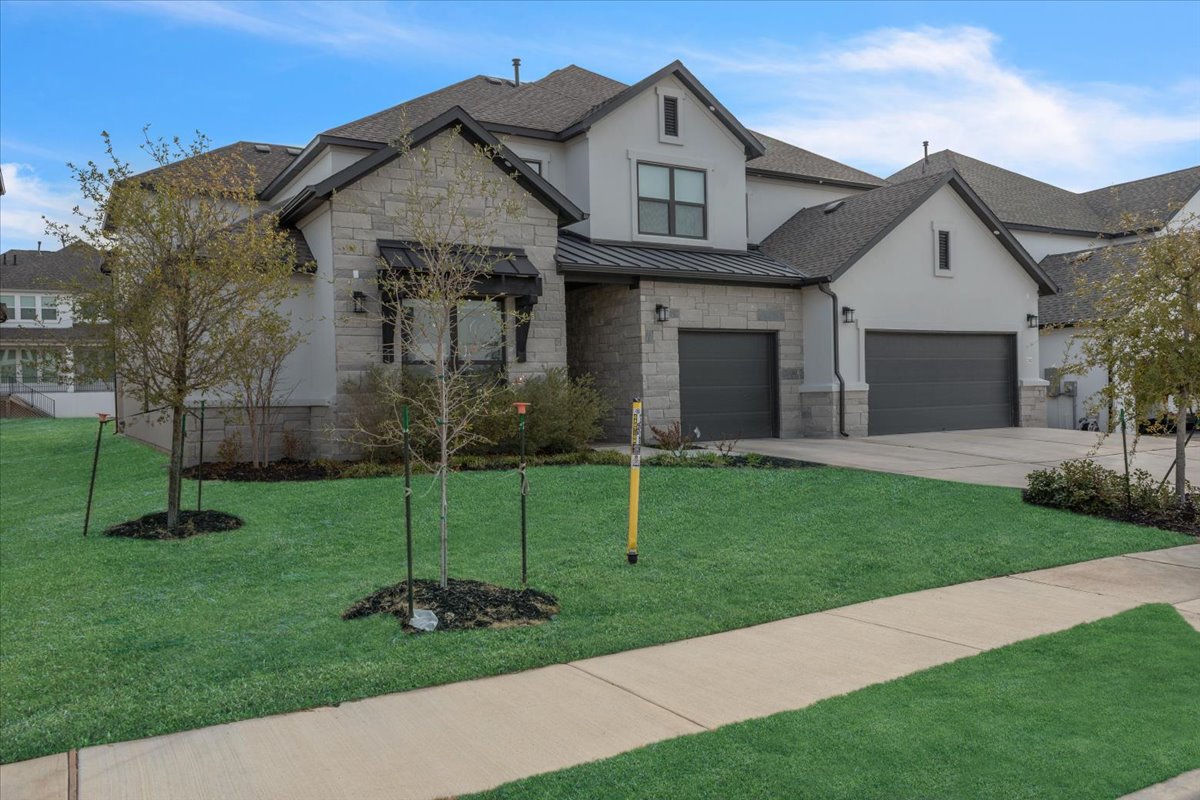 2312 Mondello Path Leander, TX 78641 - Photo 2 of 40 View of front of house featuring stone siding, a front lawn, a standing seam roof, concrete driveway, and stucco siding