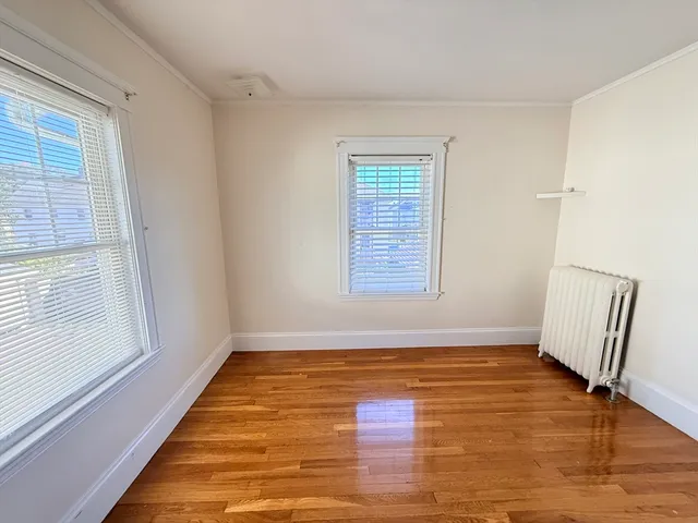 a view of an empty room with window and wooden floor