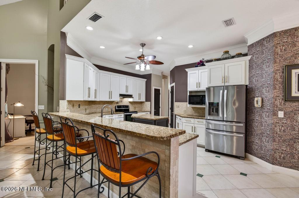 1483 Bridgette Way Fleming Island, FL 32003 - Photo 19 of 63 a kitchen with stainless steel appliances kitchen island granite countertop a sink and cabinets