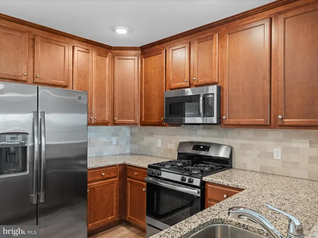 a kitchen with granite countertop stainless steel appliances a sink stove and microwave