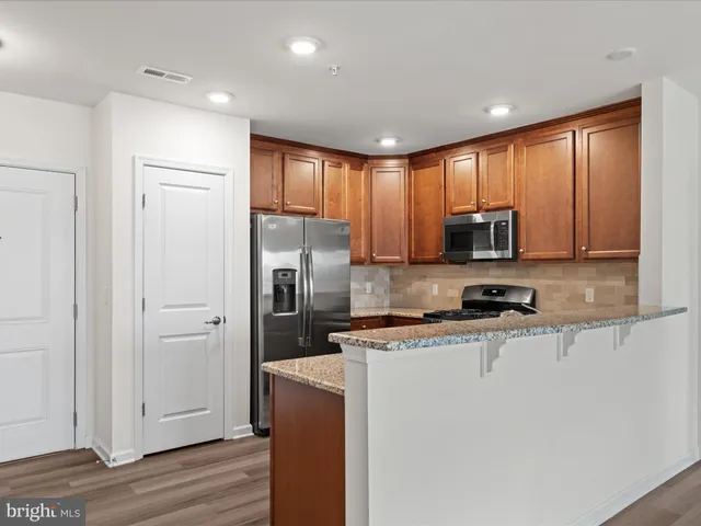 a view of a kitchen with stainless steel appliances granite countertop a stove a sink and a microwave