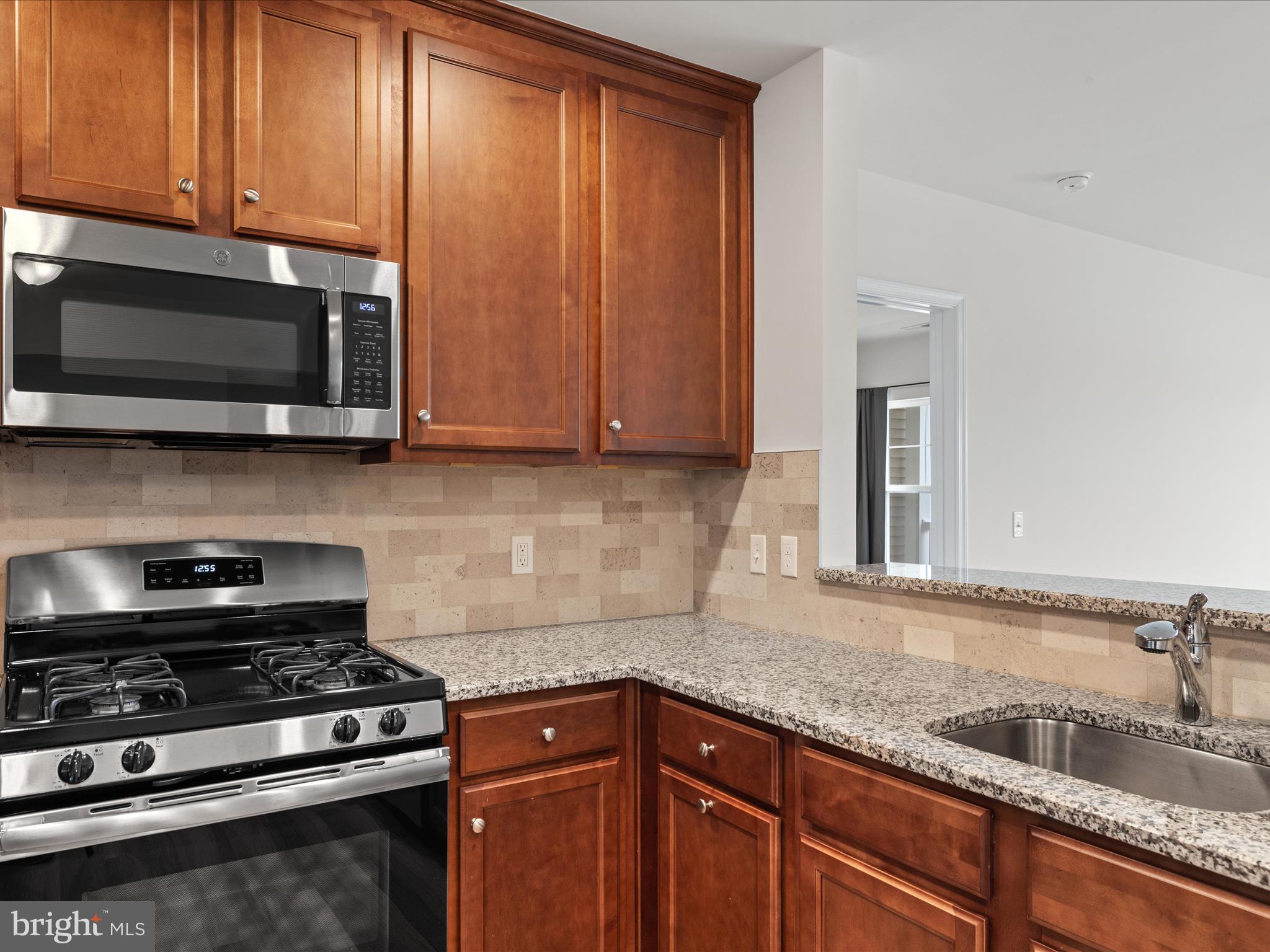 24258 Zinfandel Lane, Unit R303 Lewes, DE 19958 - Photo 15 of 82 a kitchen with granite countertop stainless steel appliances a sink stove and microwave