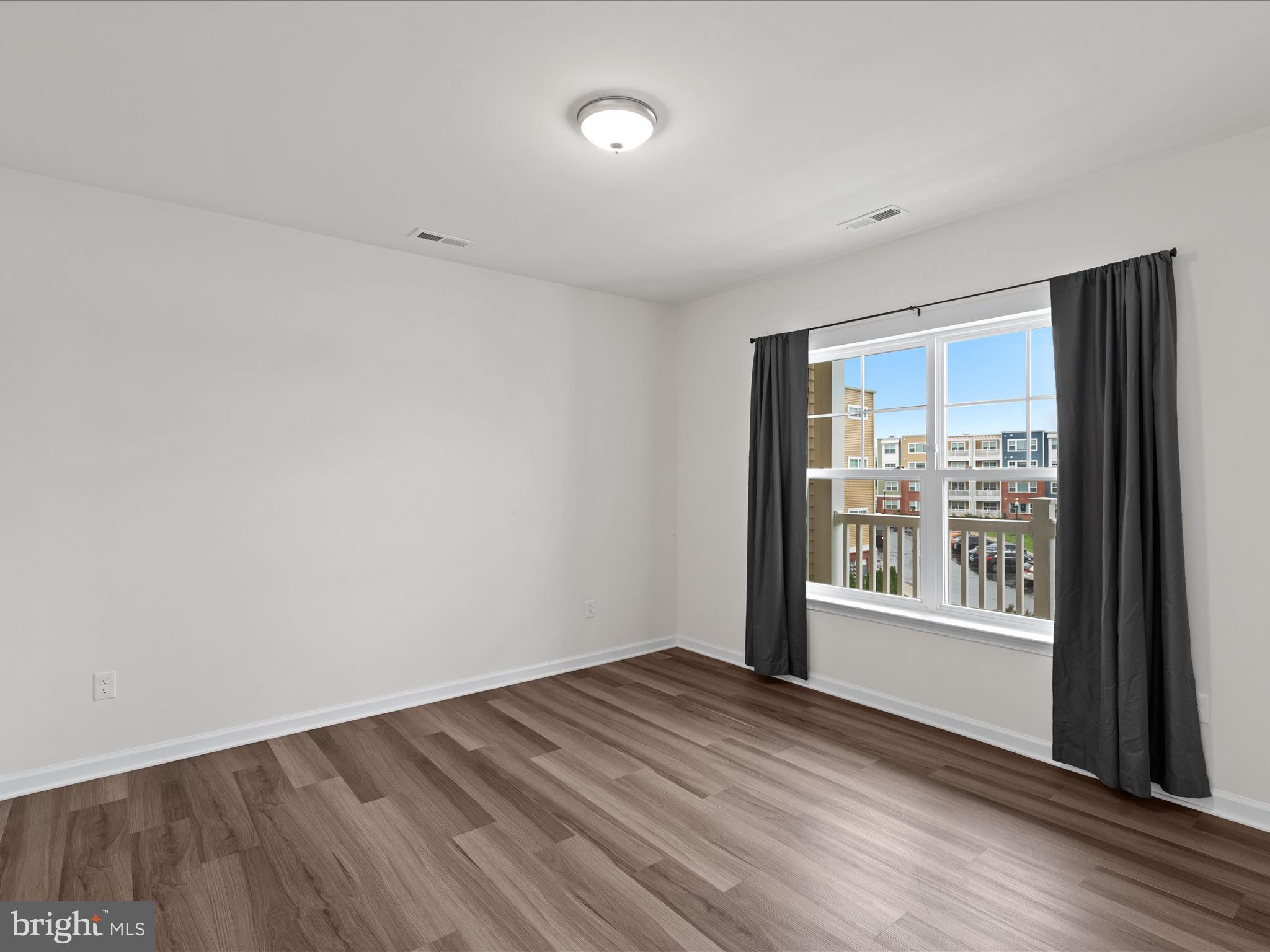 24258 Zinfandel Lane, Unit R303 Lewes, DE 19958 - Photo 39 of 82 a view of an empty room with wooden floor and a window