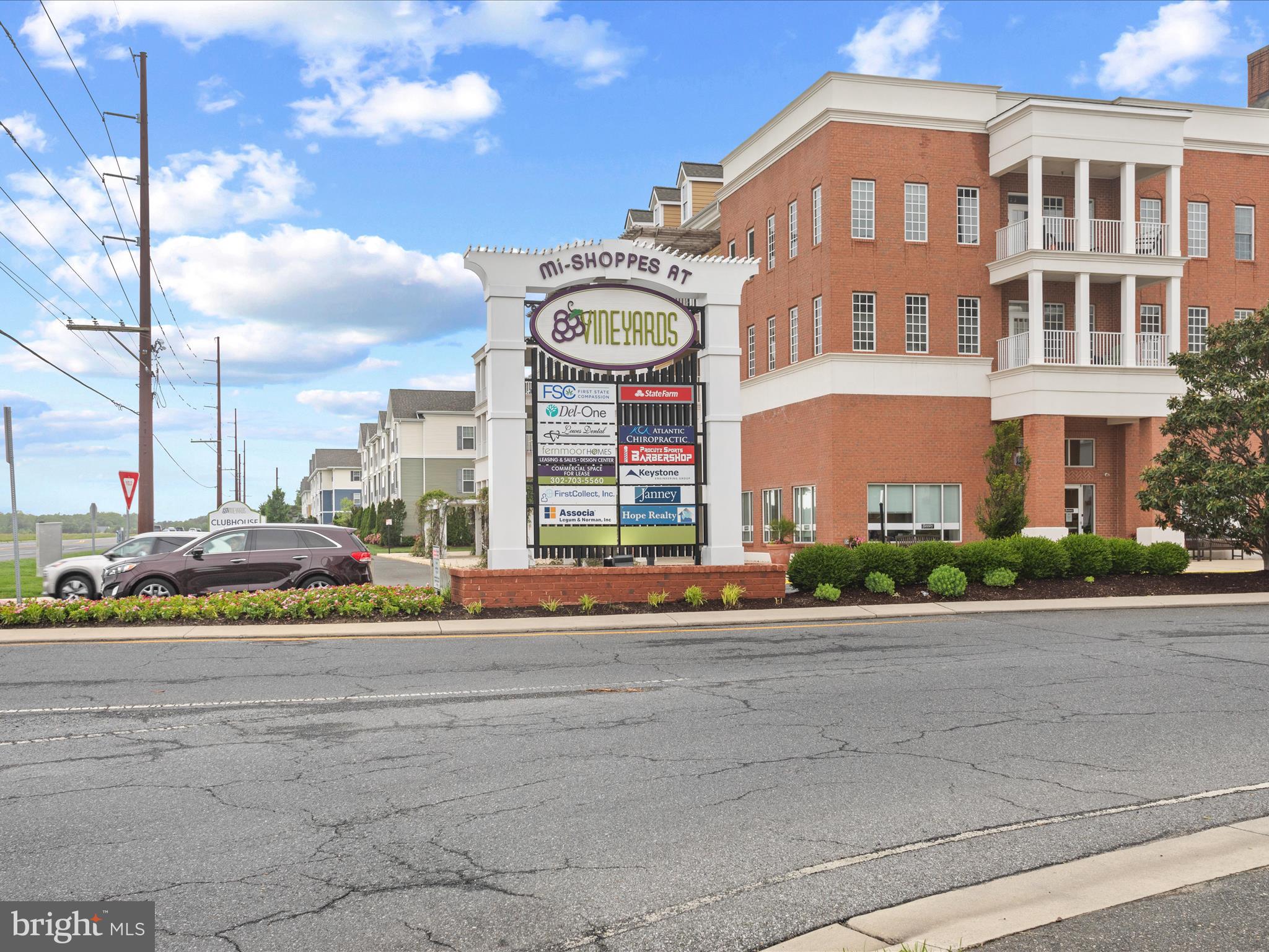 24258 Zinfandel Lane, Unit R303 Lewes, DE 19958 - Photo 82 of 82 a front view of a building with a garden and plants