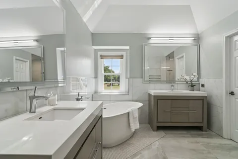 a bathroom with a sink double vanity mirror and a bathtub