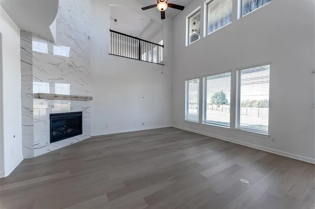 an empty room with windows fireplace and wooden floor