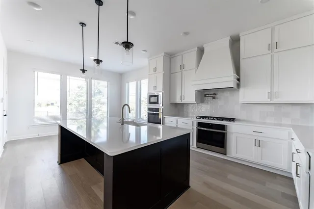 a large kitchen with stainless steel appliances granite countertop a sink a stove and a wooden floors