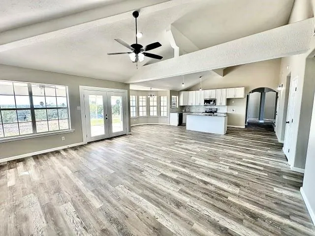 a view of an empty room with window and wooden floor
