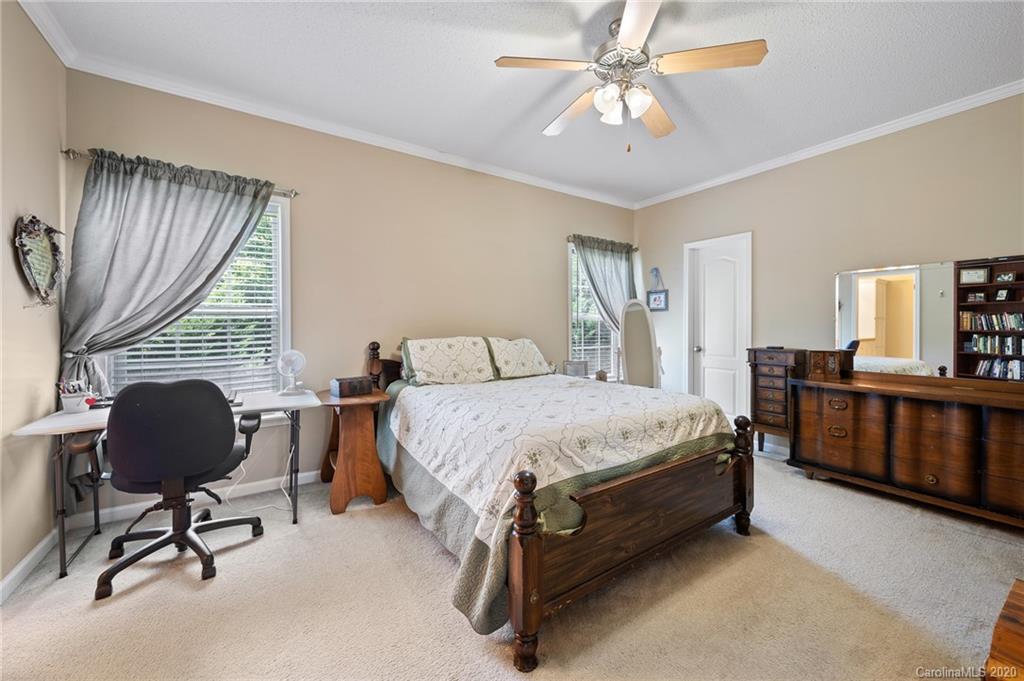 135 Ridge Field Drive Hendersonville, NC 28792 - Photo 13 of 28 a spacious bedroom with a bed a desk chair and windows