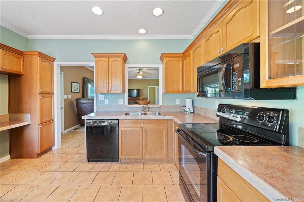 135 Ridge Field Drive Hendersonville, NC 28792 - Photo 9 of 28 a kitchen with stainless steel appliances granite countertop a stove top oven a sink a counter space and cabinets