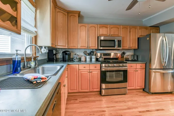 a kitchen with stainless steel appliances a dining table chairs refrigerator and microwave