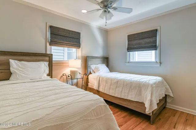 a bedroom with a bed a dresser and wooden floor