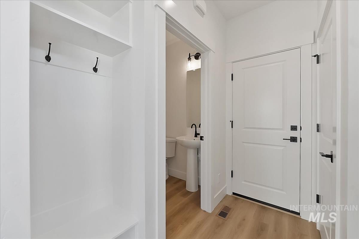 776 South Calhoun Lane Star, ID 83669 - Photo 39 of 49 Entryway featuring a built-in bench with storage and coat hooks, a white panel door with matte black hardware, and wood-finish flooring