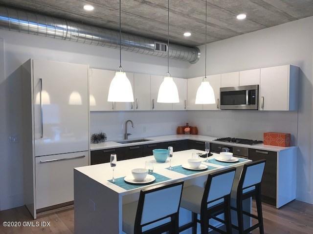 16 Old Track Road, Unit PH #3 Greenwich, CT 06830 - Photo 8 of 21 a kitchen with stainless steel appliances kitchen island a table chairs in it and wooden floors