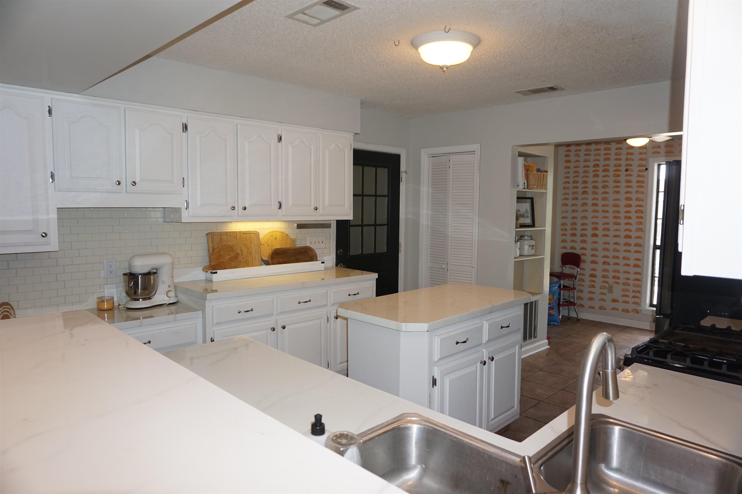 3780 Meade Lake Road Millington, TN 38053 - Photo 16 of 40 Kitchen with white cabinetry, light countertops, tasteful backsplash, dark tile patterned flooring, and a textured ceiling
