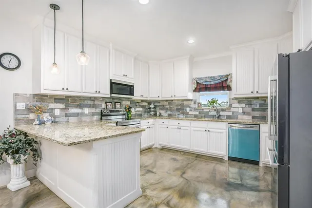 a kitchen with kitchen island granite countertop white cabinets a sink stove and refrigerator