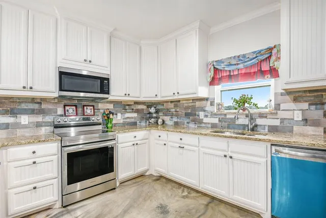 a kitchen with granite countertop white cabinets white stainless steel appliances and sink