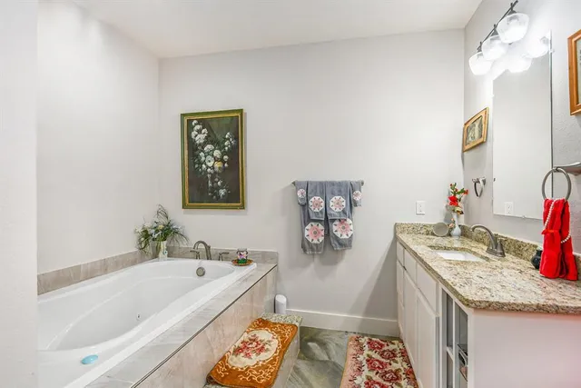 a bathroom with a granite countertop tub sink and mirror