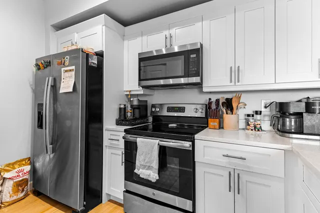 a kitchen with stainless steel appliances white cabinets and a stove top oven
