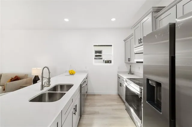 a kitchen with stainless steel appliances granite countertop a sink a stove and a refrigerator with wooden floor