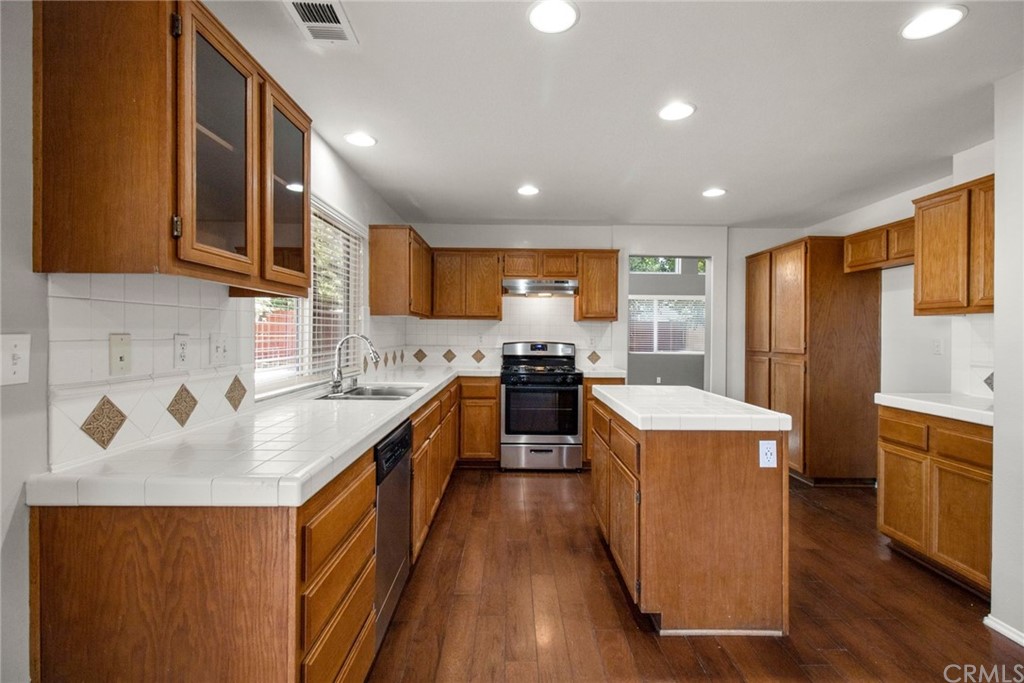 28346 Saddlecrest Street Menifee, CA 92585 - Photo 11 of 35 a kitchen with refrigerator a sink a stove and wooden cabinets
