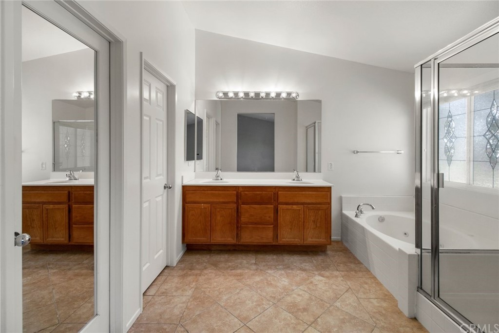 28346 Saddlecrest Street Menifee, CA 92585 - Photo 17 of 35 a bathroom with a granite countertop tub double vanity sink and a mirror