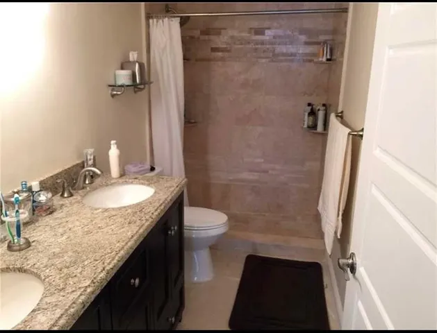 a bathroom with a granite countertop sink toilet and shower