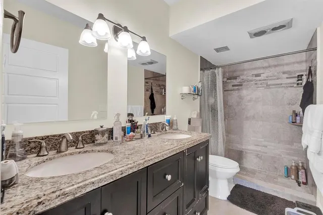a bathroom with a granite countertop sink toilet a mirror a vanity and shower