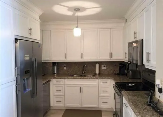a kitchen with white cabinets and refrigerator