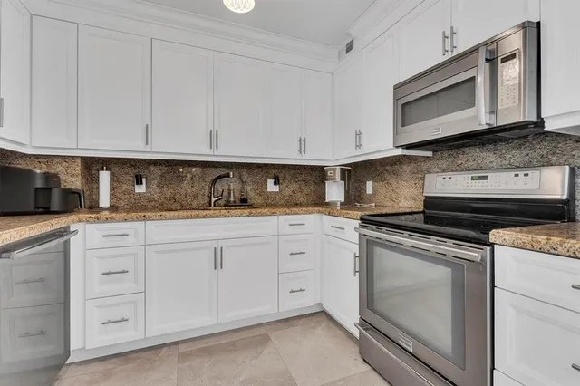 a kitchen with granite countertop white cabinets stainless steel appliances and sink